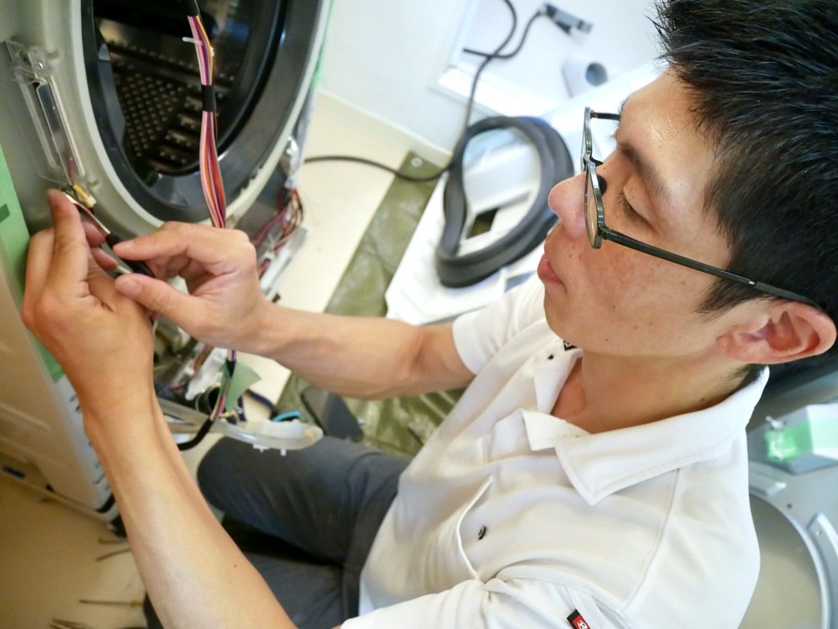 ドラム式洗濯機を分解洗浄している作業の様子