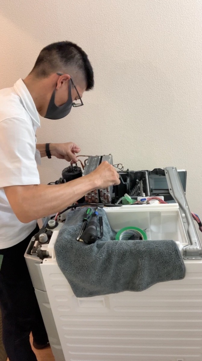 ドラム式洗濯機の内部を手作業で分解しているところ